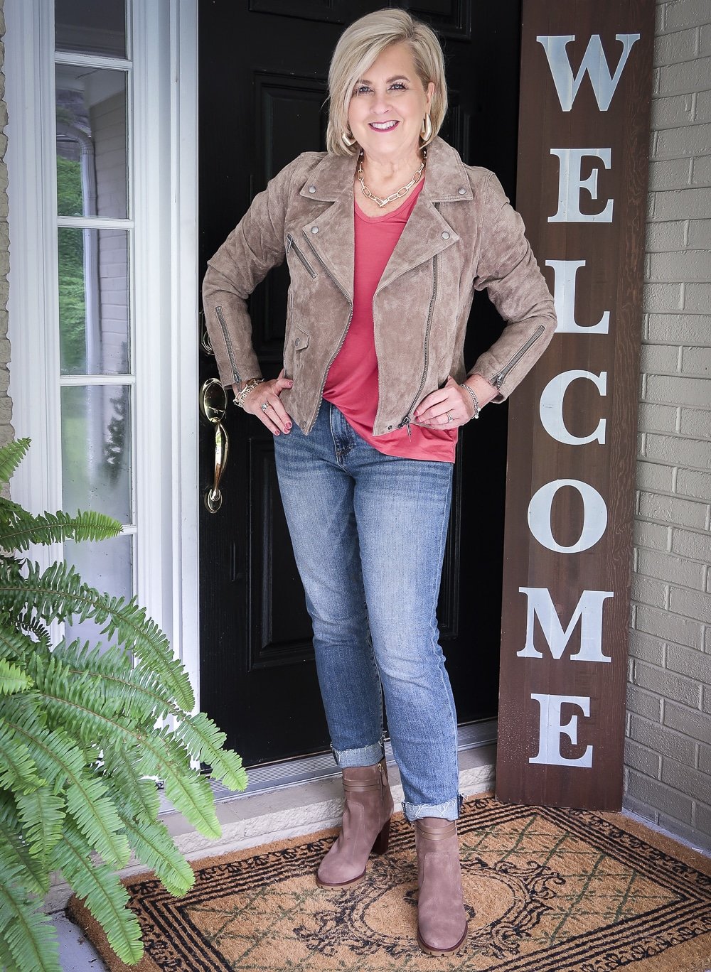 Fashion Blogger 50 Is Not Old is wearing a coral v-neck tunic, a suede moto jacket, and cuffed jeans with Tory Burch boots