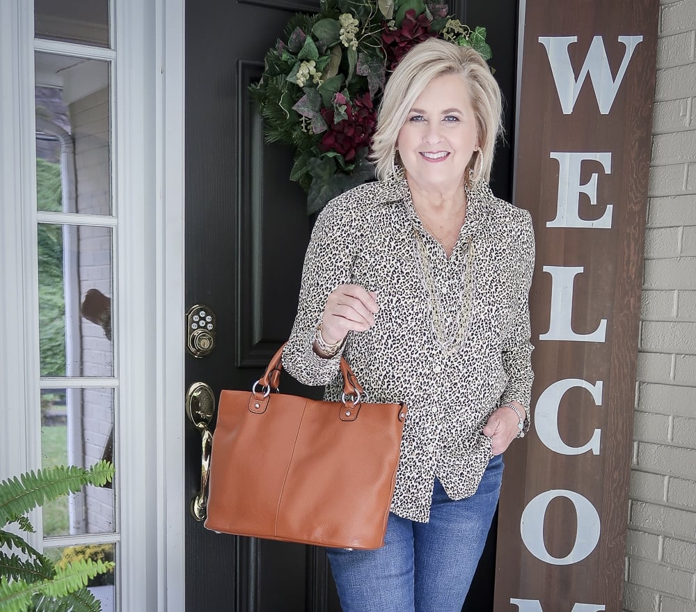 Fashion Blogger 50 Is Not Old is wearing an animal print button up shirt and carrying a brown leather handbag