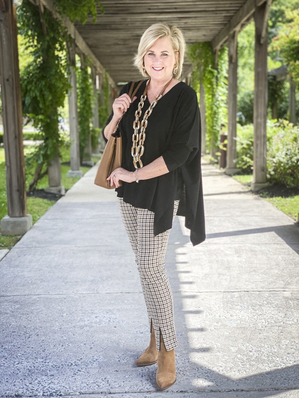Fashion Blogger 50 Is Not Old is wearing plaid pants with a black poncho and taupe ankle boots