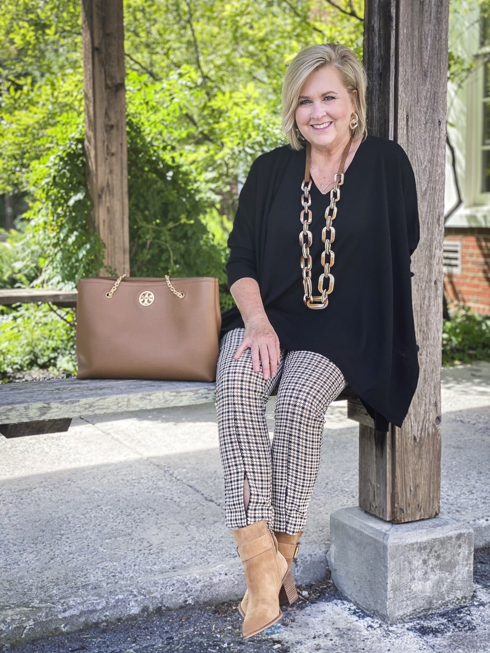Fashion Blogger 50 Is Not Old is wearing plaid pants in the fall with a black poncho, a long ombre necklace, and taupe ankle boots