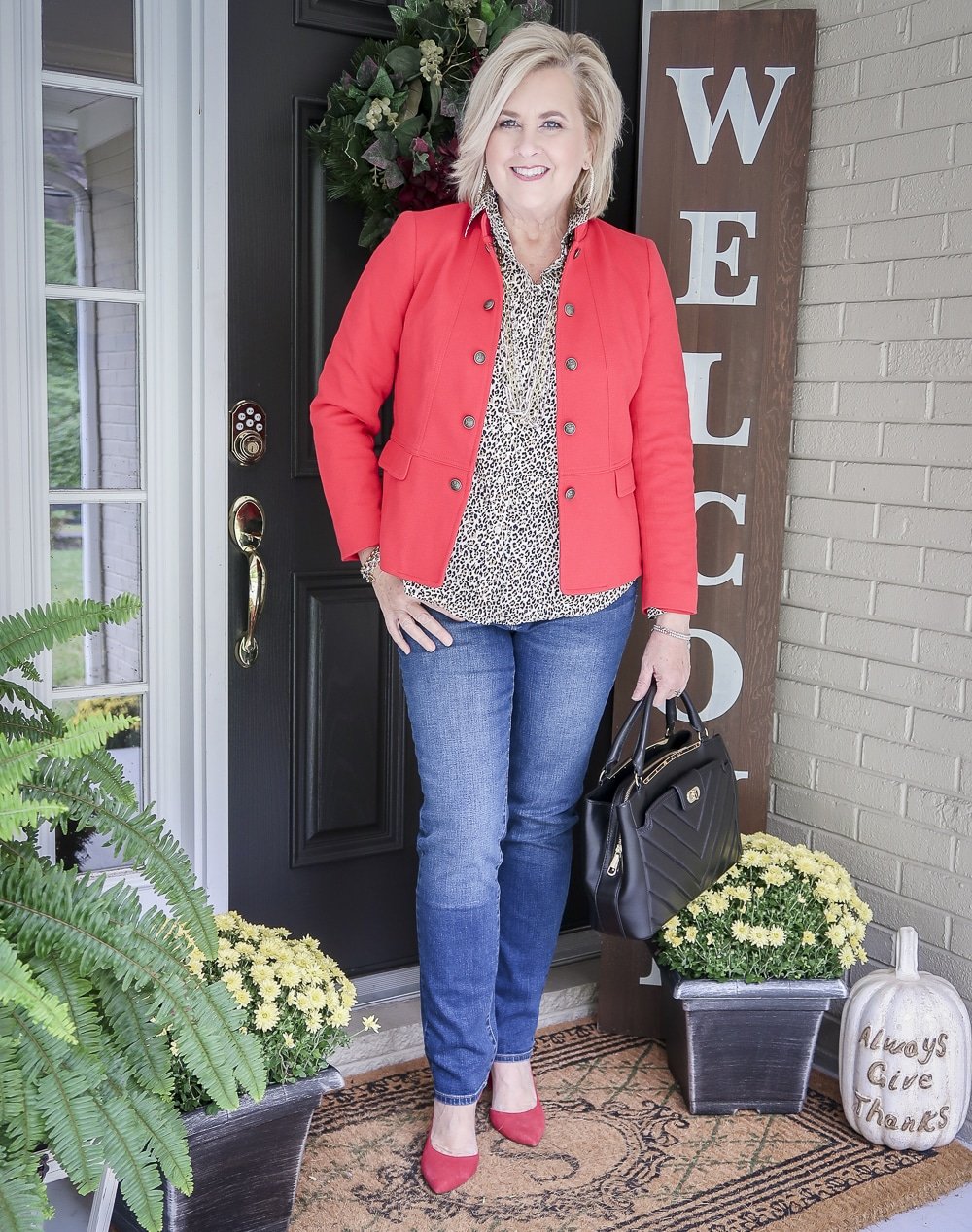 Fashion Blogger 50 Is Not Old in a fall try-on session wearing a red knit jacket, a leopard print button up top, and ankle jeans from Chicos, and red high heel pumps