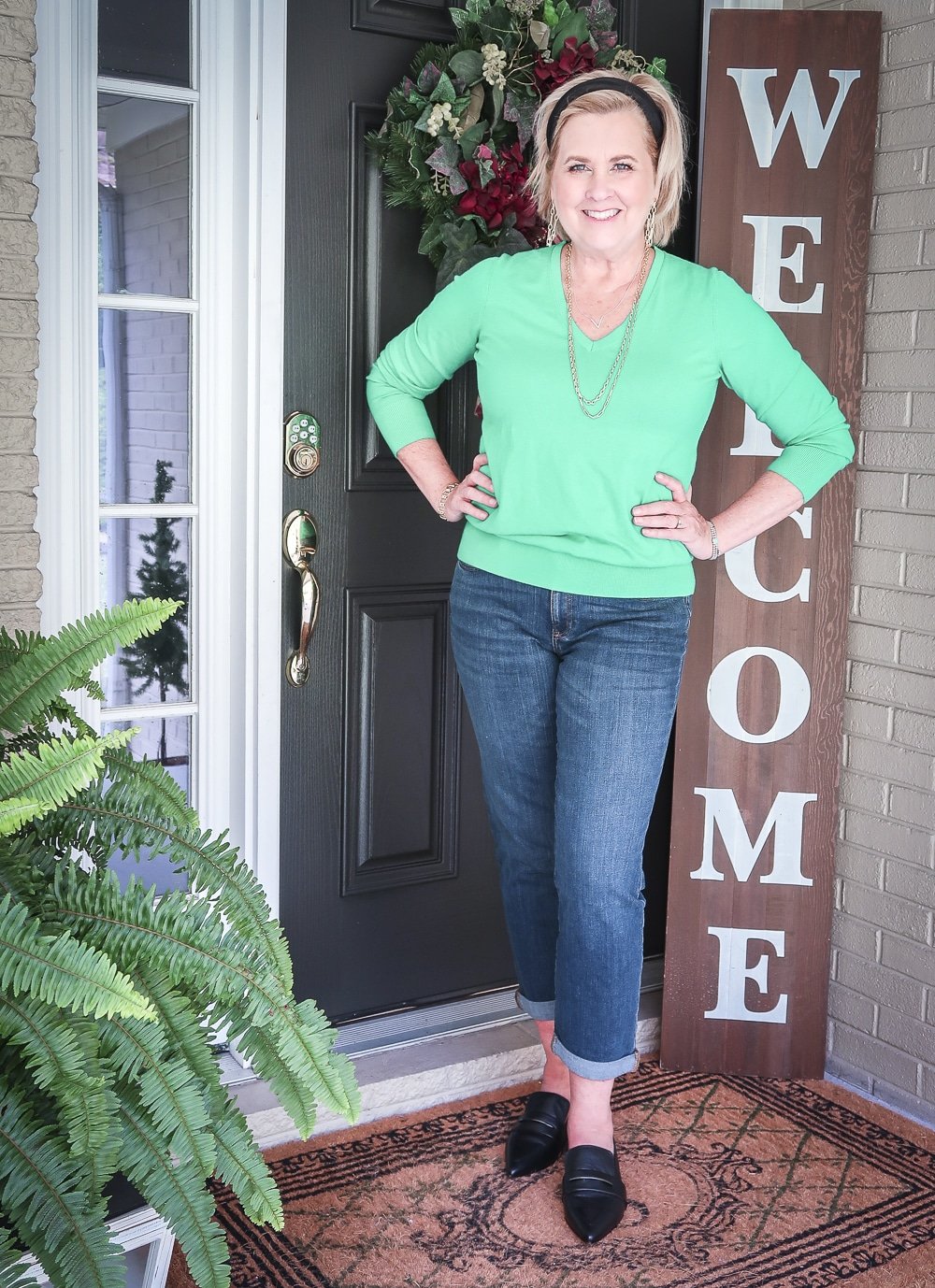 Fashion Blogger 50 Is Not Old is wearing an emerald green sweater, girlfriend jeans, and pointed-toe loafers