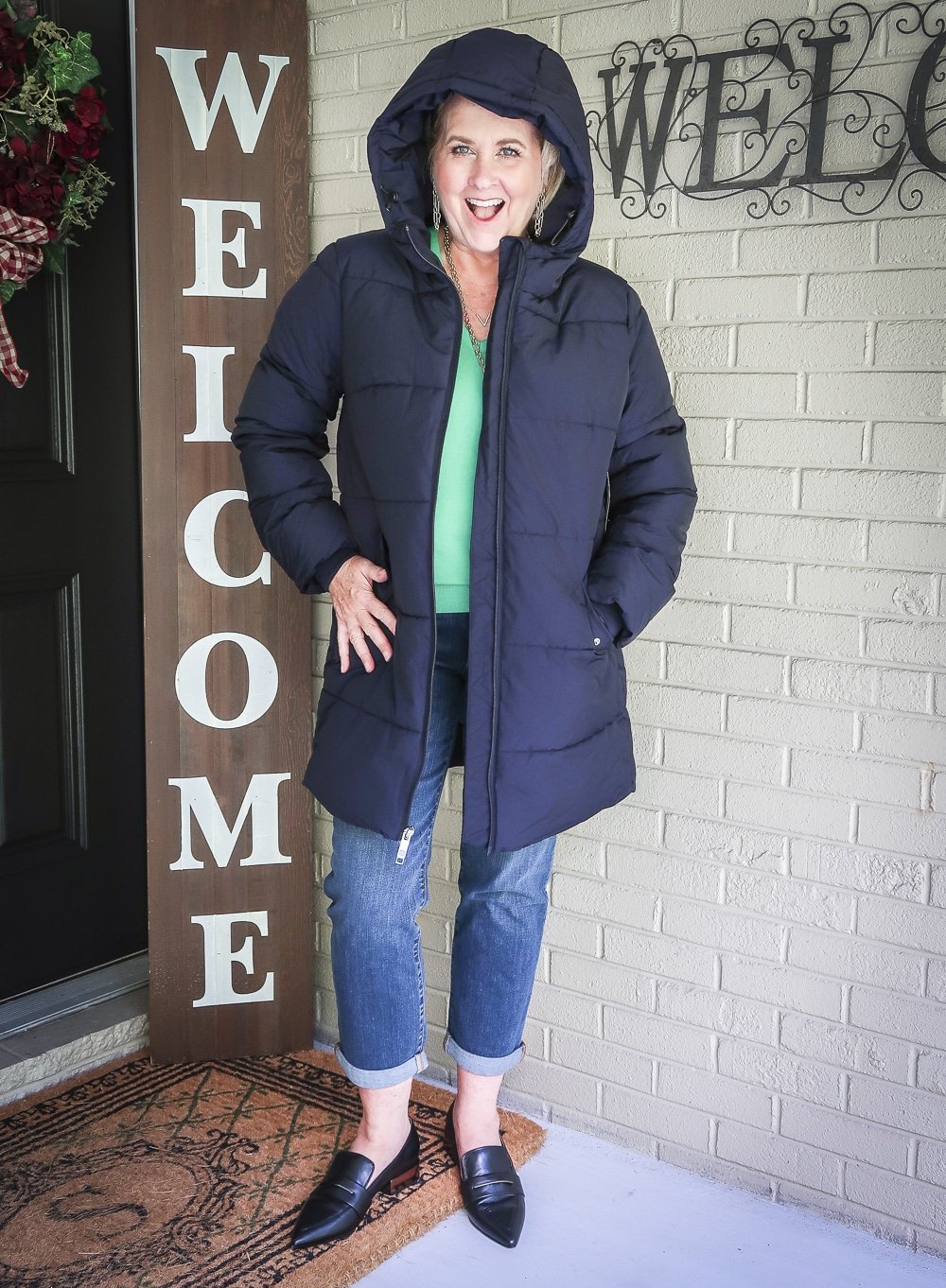 Fashion Blogger 50 Is Not Old is wearing a navy puffer coat, girlfriend crop jeans, and black pointy loafers