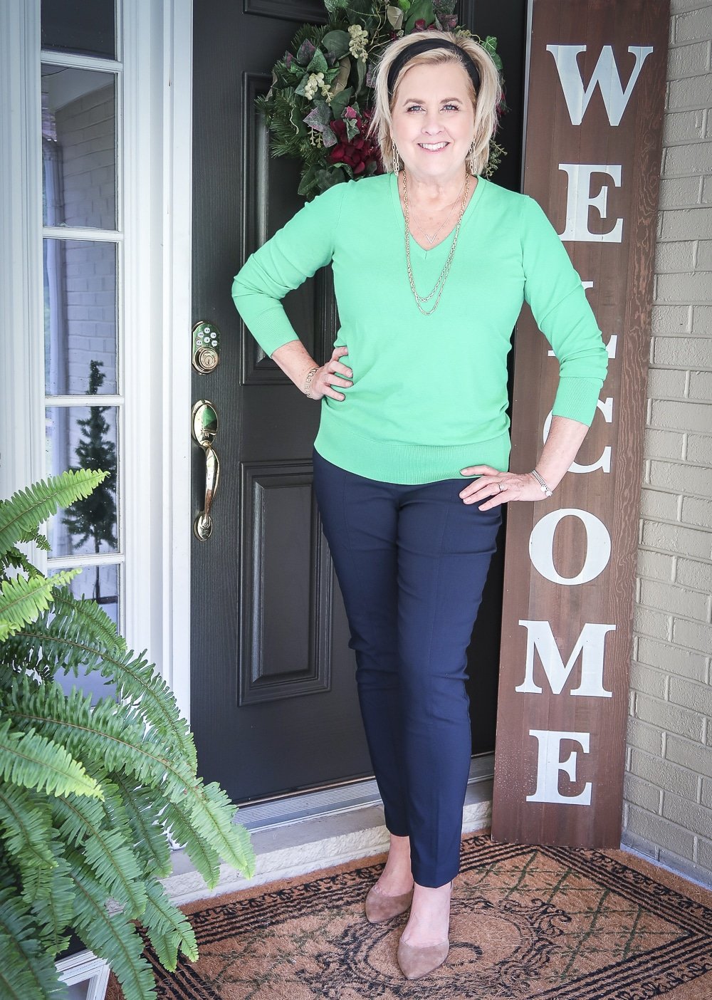 Fashion Blogger 50 Is Not Old is wearing an Emerald green sweater, navy dress pants, and neutral heels