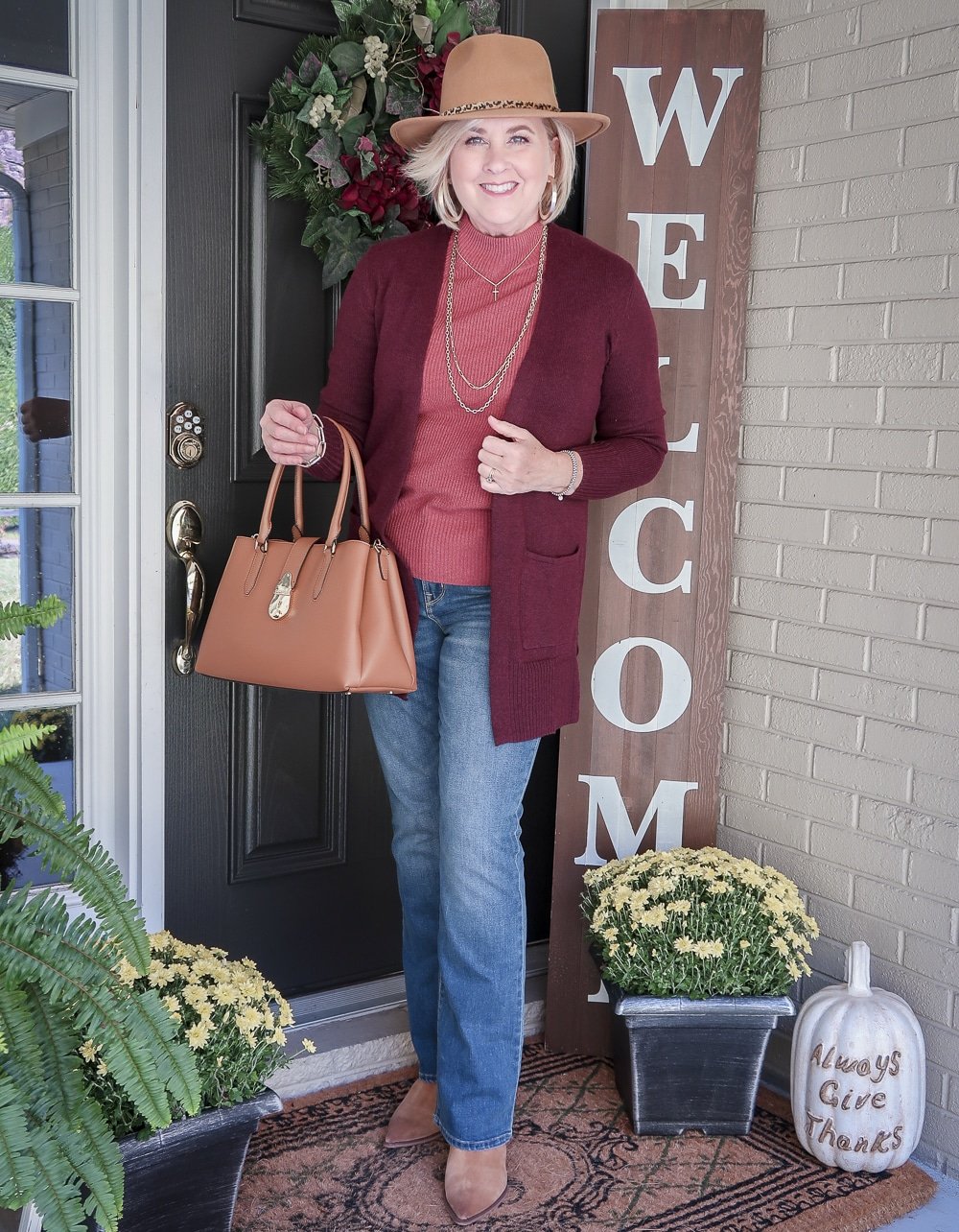 Fashion Blogger 50 Is Not Old is wearing a brown Fedora with a maroon cardigan, a rose colored sweater, blue jeans, and pointy ankle boots
