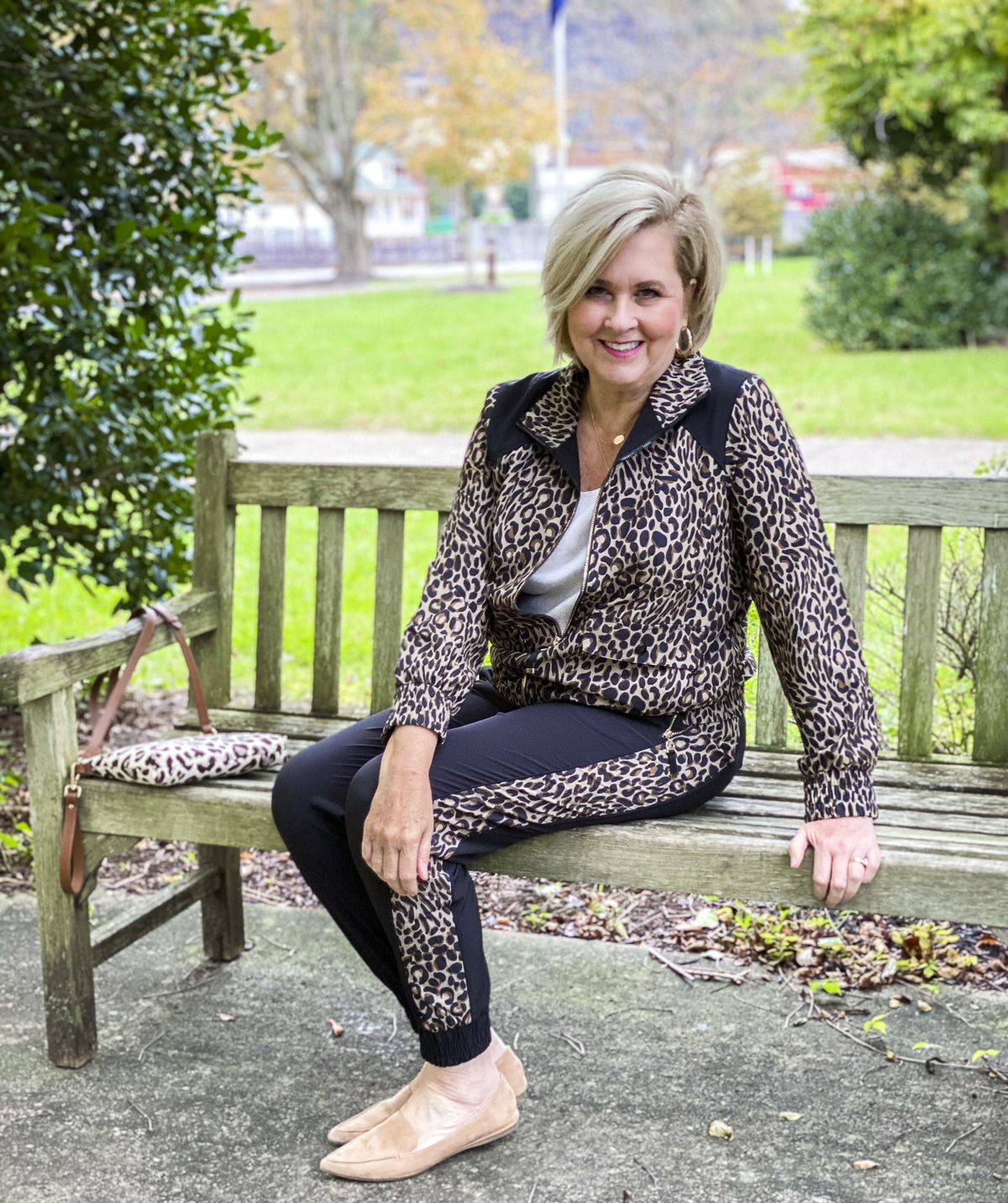 Fashion Blogger 50 Is Not Old is on a bench in a Cheetah print jacket and joggers from Chicos