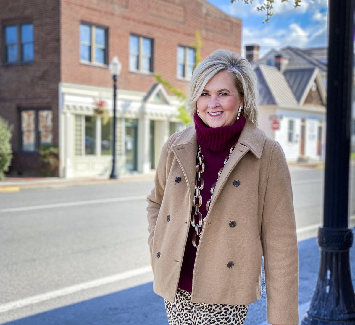 Fashion Blogger 50 Is Not Old is wearing a maroon turtleneck sweater, and a camel peacoat from J. Crew