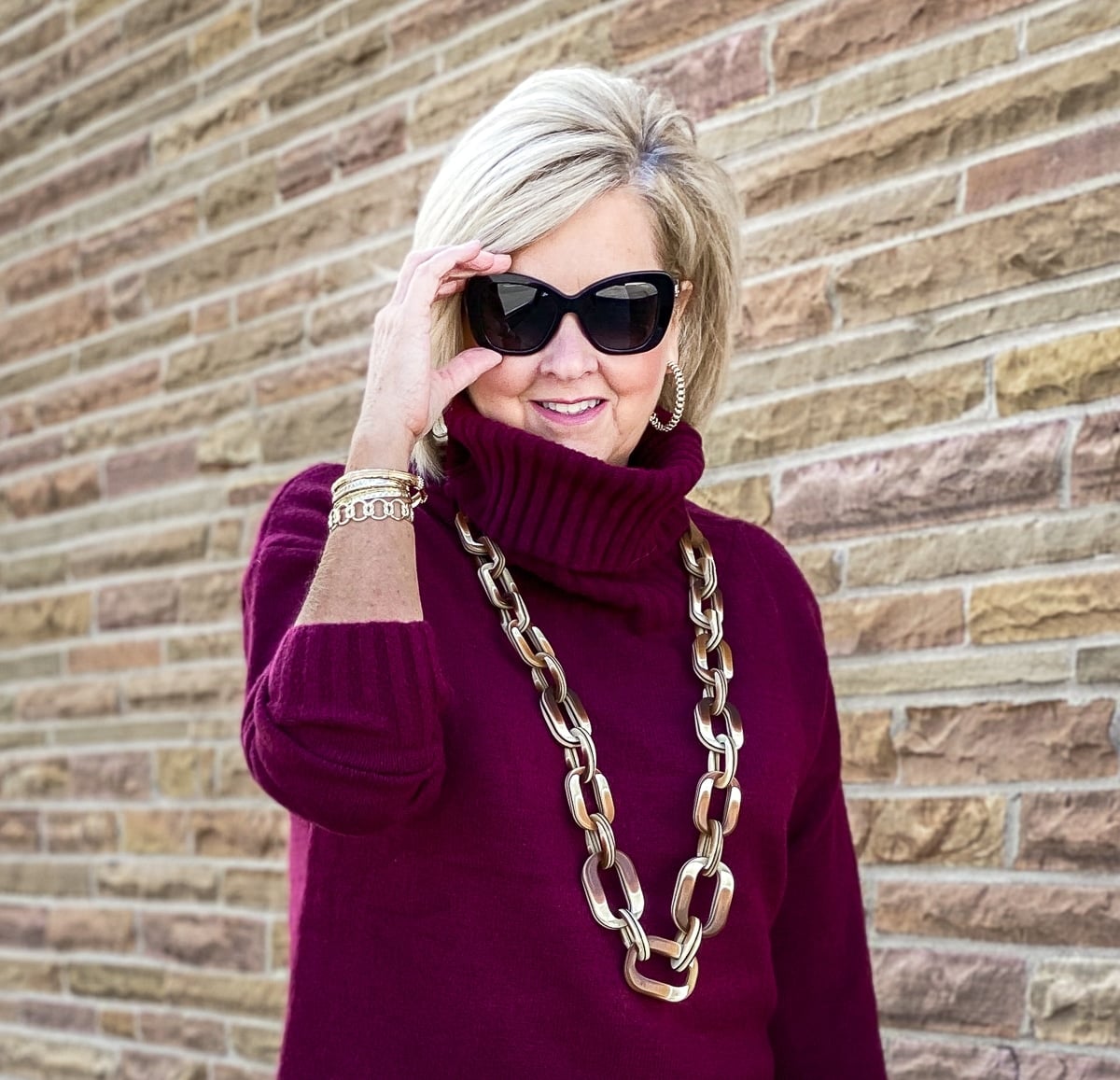 Fashion Blogger 50 Is Not Old is wearing a maroon turtleneck sweater with Versace sunglasses and an Ombre resin necklace from Chicos