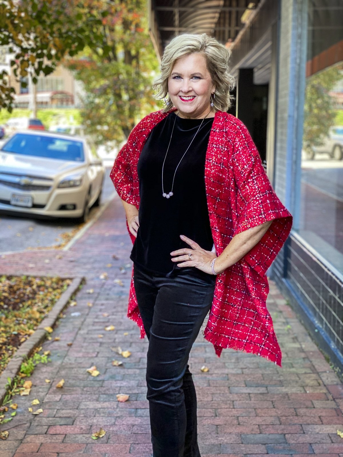 Fashion Blogger 50 Is Not Old is wearing a black velvet top and pants with a red Ruana
