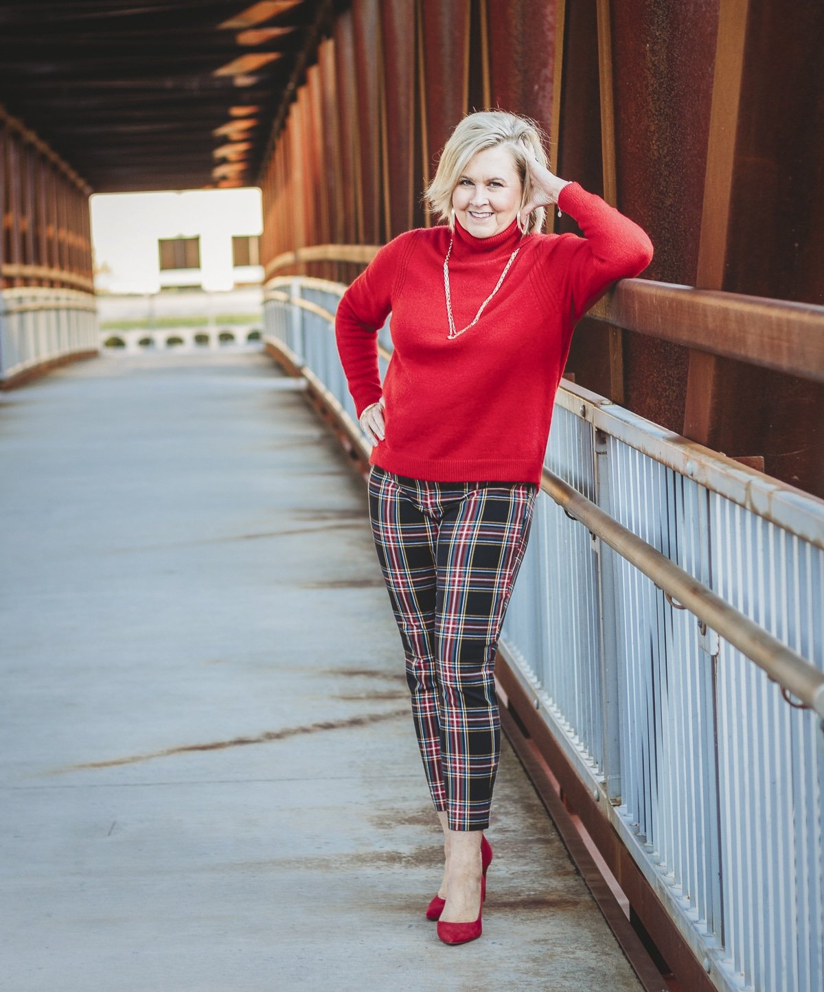 Fashion Blogger 50 Is Not Old is looking festive in this red turtleneck sweater and plaid pants with red pump heels