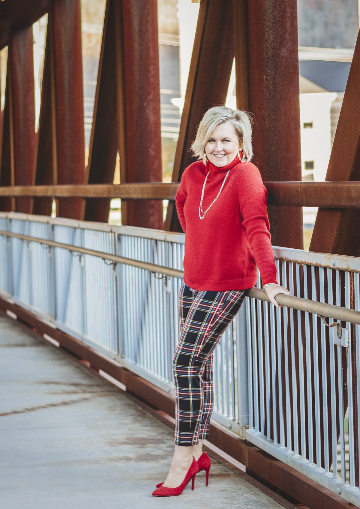 Fashion Blogger 50 Is Not Old is looking festive in this red turtleneck sweater and plaid pants with red heels