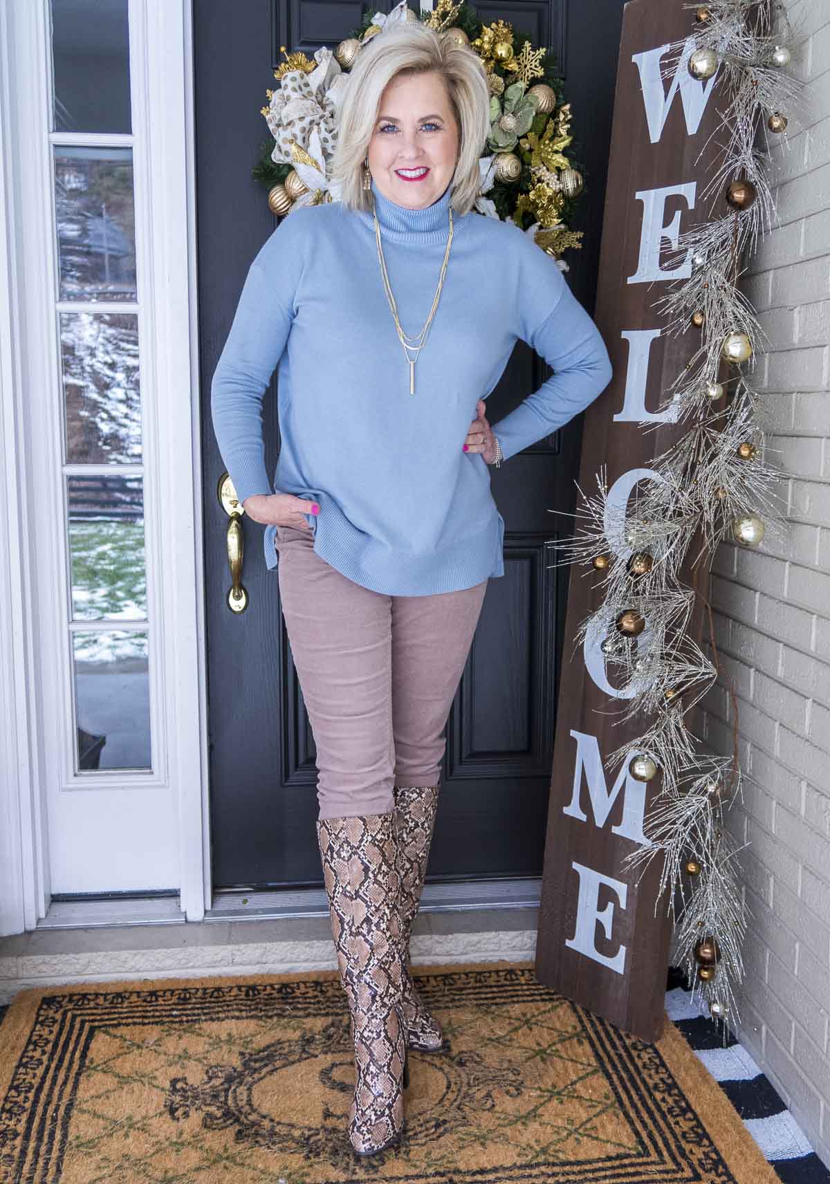Fashion Blogger 50 Is Not Old is wearing a blue turtleneck sweater with a pair of taupe corduroy skinny pants from Loft. A pair of snake skin knee boots from Target finished the look.