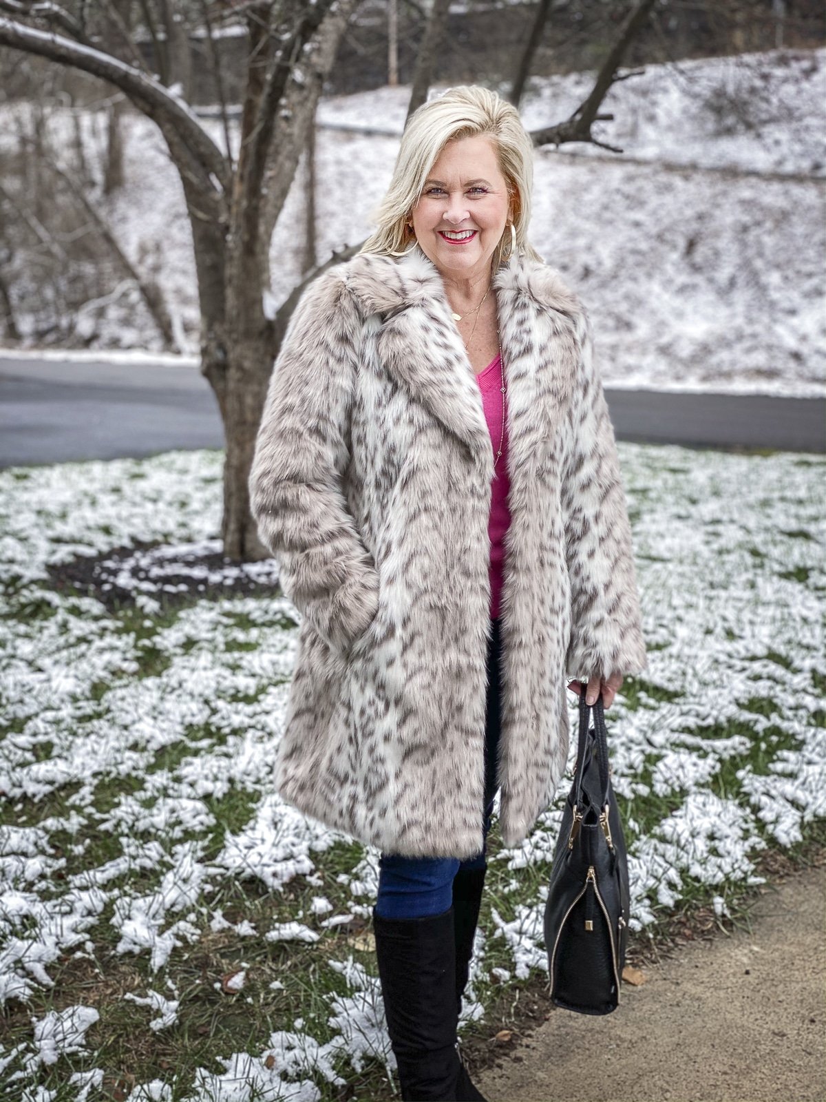 FASHION BLOGGER 50 IS NOT OLD is wearing a faux-fur coat by Karl Lagerfeld with a bright pink v-neck cashmere sweater, skinny jeans, and black suede boots