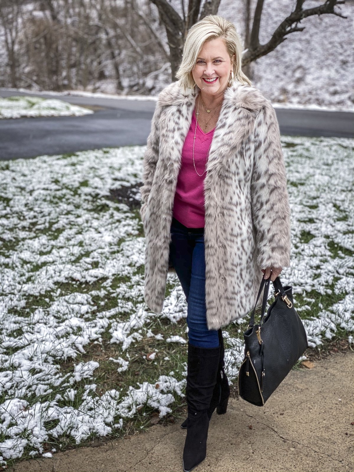 FASHION BLOGGER 50 IS NOT OLD is wearing a faux fur coat by Karl Lagerfeld with a bright pink v-neck cashmere sweater, skinny jeans, and black suede boots