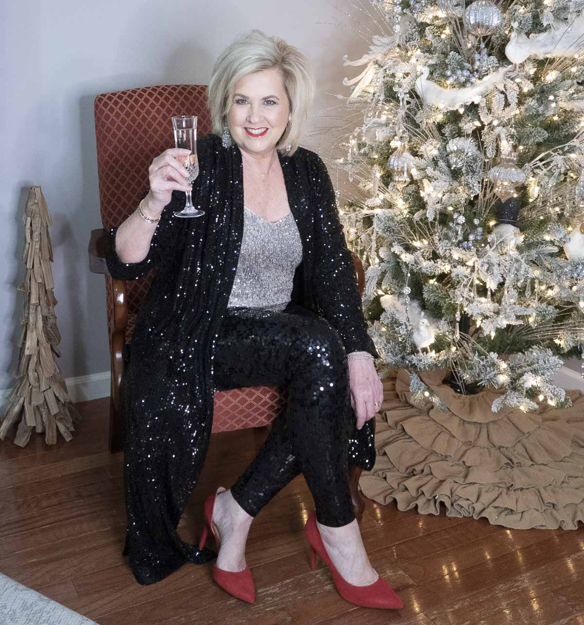 Fashion Blogger 50 Is Not Old is sitting in a chair in a sequined outfit to ring in the New Year