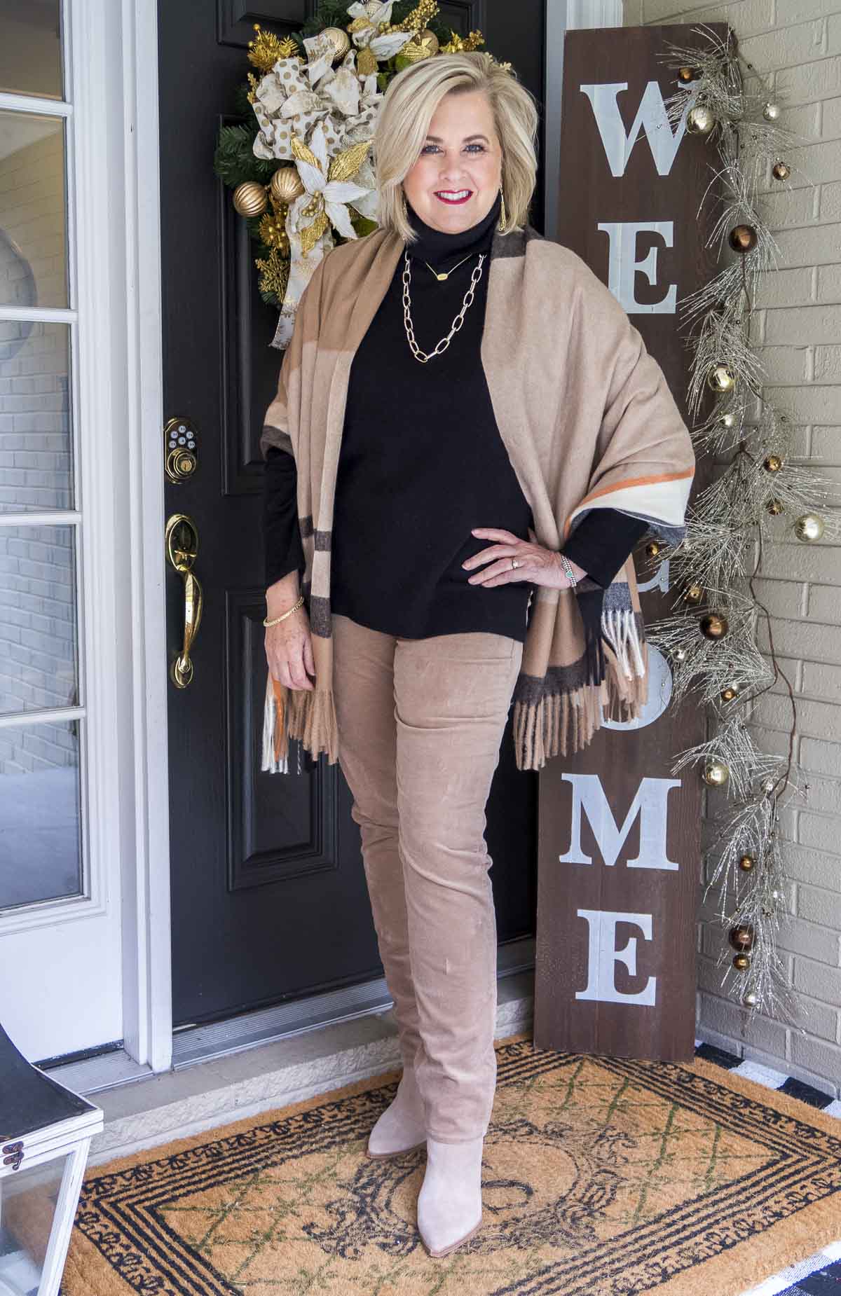Fashion Blogger 50 Is Not Old is styling a black cashmere turtleneck sweater, a blanket scarf, and taupe corduroy pants