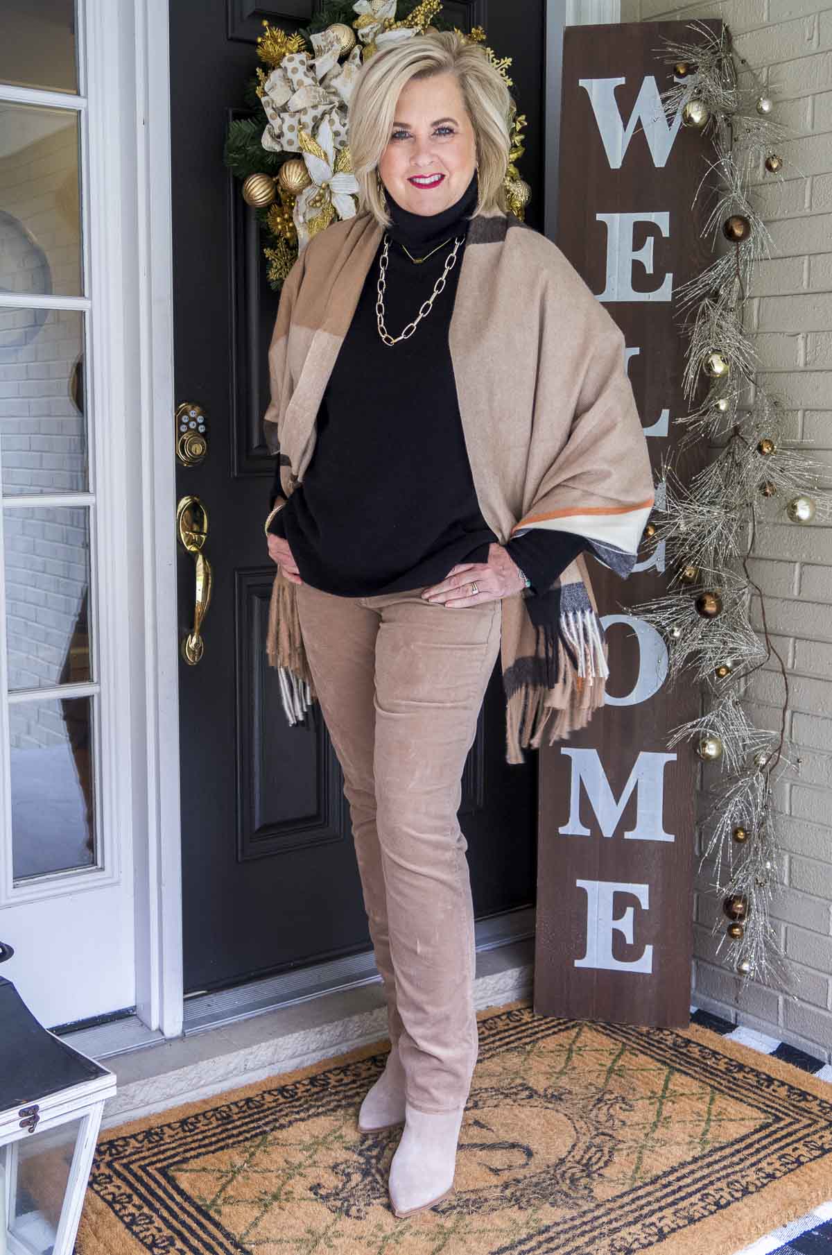 Fashion Blogger 50 Is Not Old is styling a classic look with a black cashmere turtleneck sweater, a plaid scarf, and taupe corduroy pants