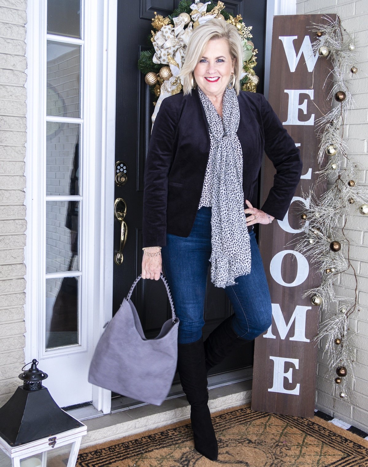 Fashion Blogger 50 Is Not Old is wearing a cheetah print camisole and scarf with a black velvet jacket, skinny jeans, black suede knee boots, and a gray hobo bag
