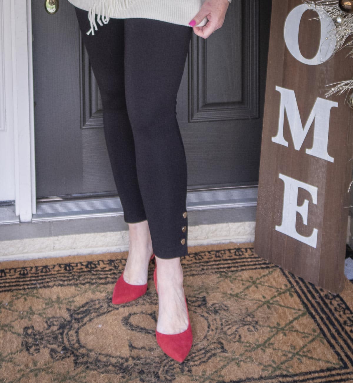 Fashion Blogger 50 Is Not Old is styling a pair of black snap leggings, and red suede pumps