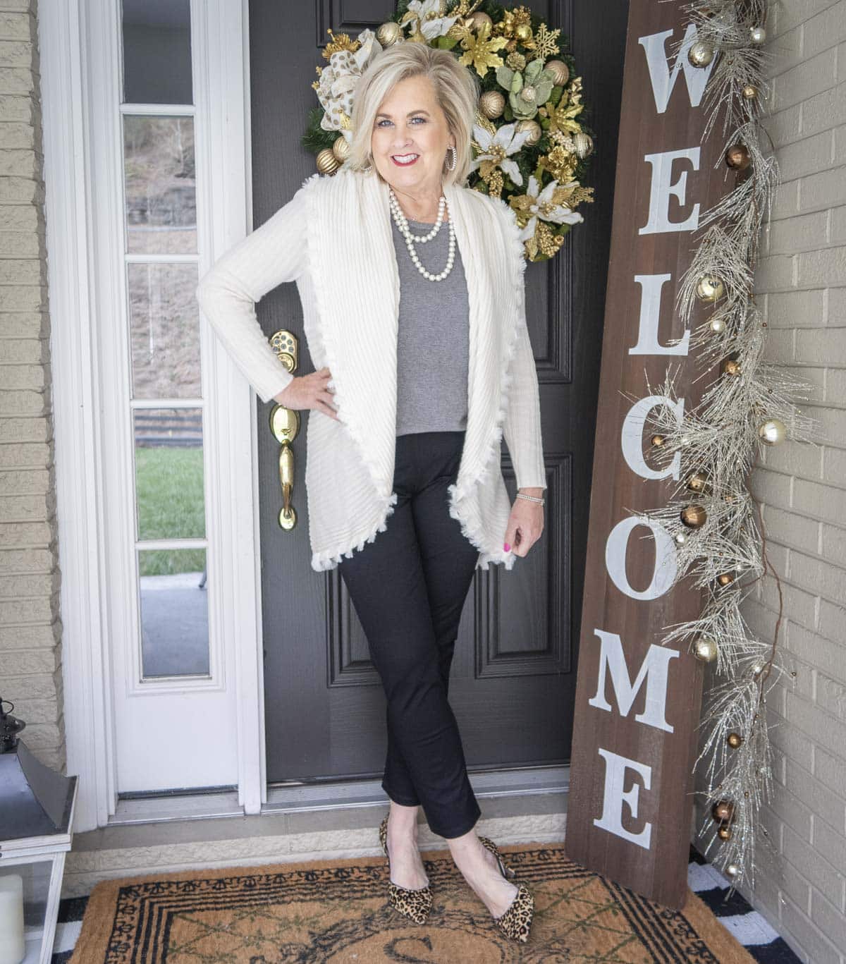 Fashion Blogger 50 Is Not Old is wearing a gray tank with an Ecru colored cocoon cardigan with a large collar, black jeans, and leopard print heels