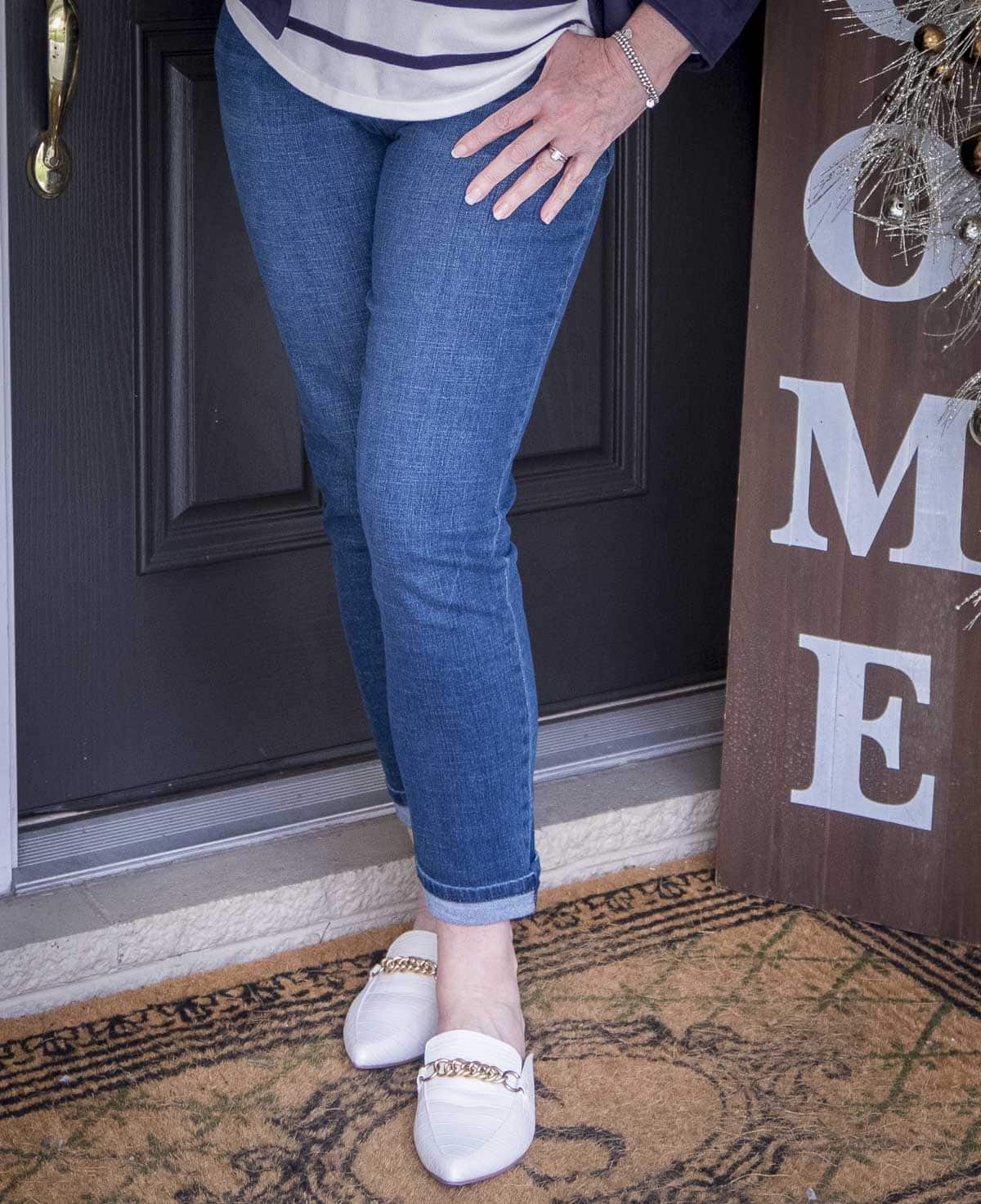 Fashion Blogger 50 Is Not Old is wearing medium wash jeans and bone chain link mules