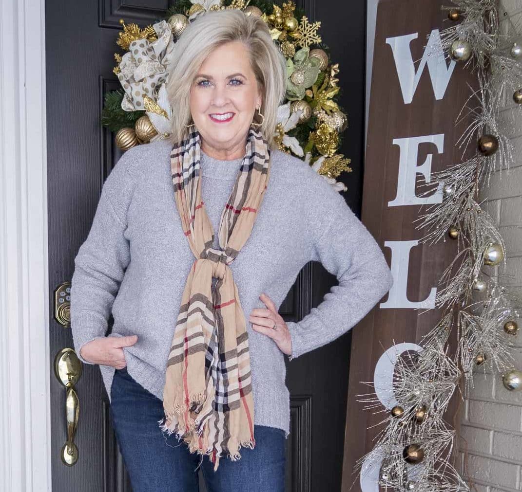 Fashion Blogger 50 Is Not Old is wearing a gray crewneck sweater and a plaid scarf
