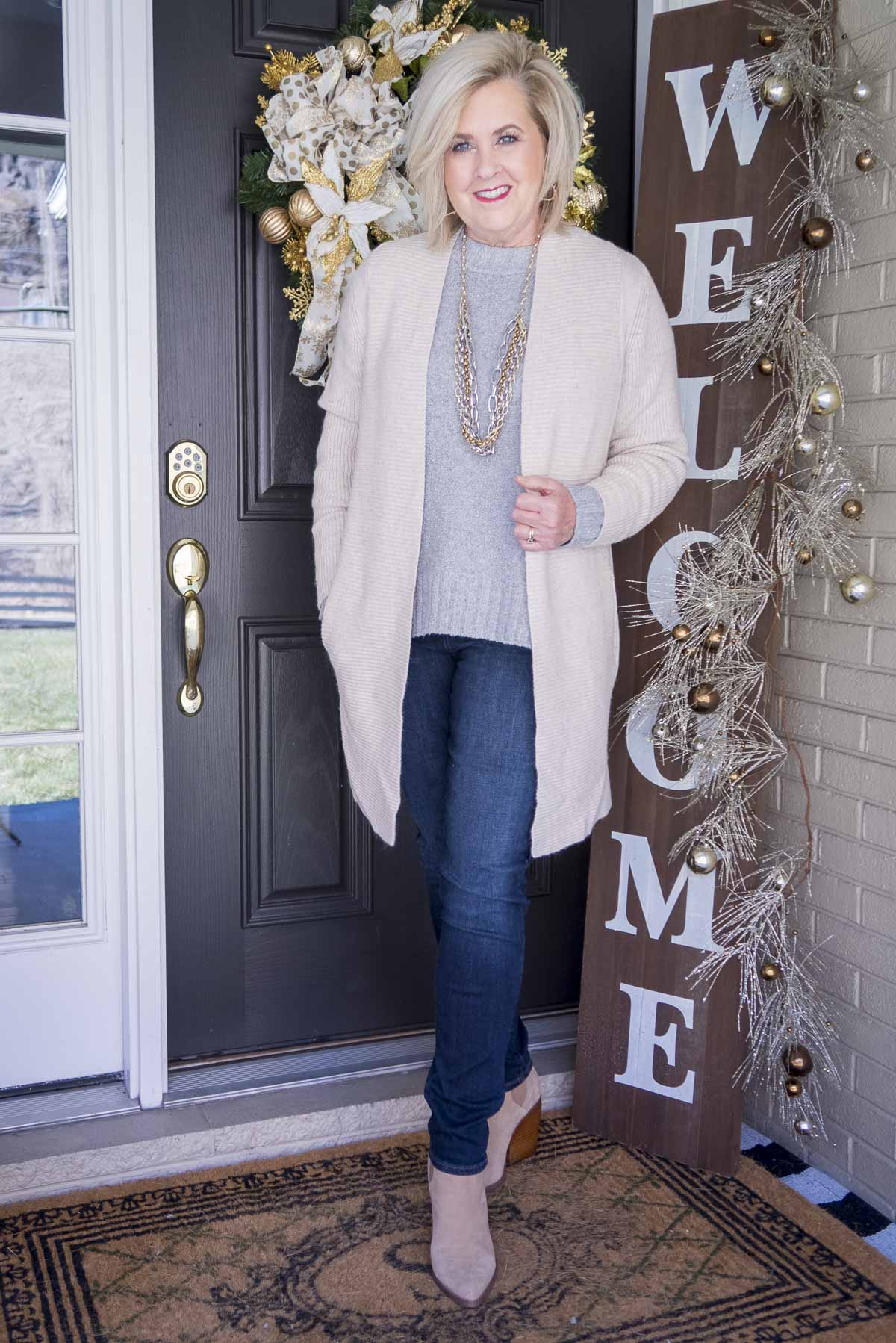 Fashion Blogger 50 Is Not Old is wearing a gray crewneck sweater, a long beige cashmere blend cardigan from Chico's, a statement necklace by Kendra Scott, skinny jeggings, and pointy toe ankle boots