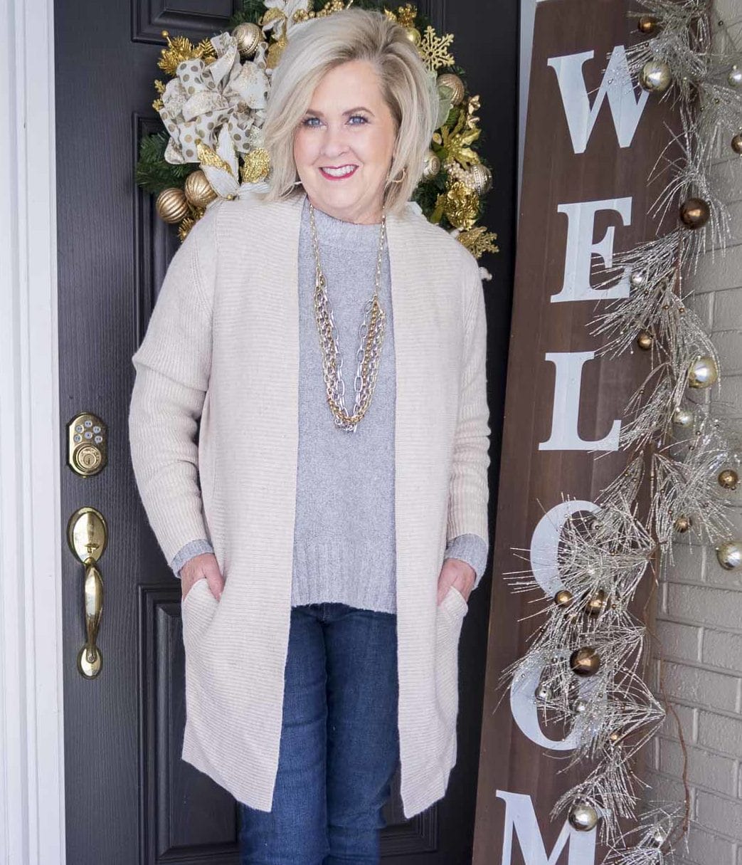 Fashion Blogger 50 Is Not Old is wearing a gray crewneck sweater, a long beige cardigan, and a statement necklace by Kendra Scott