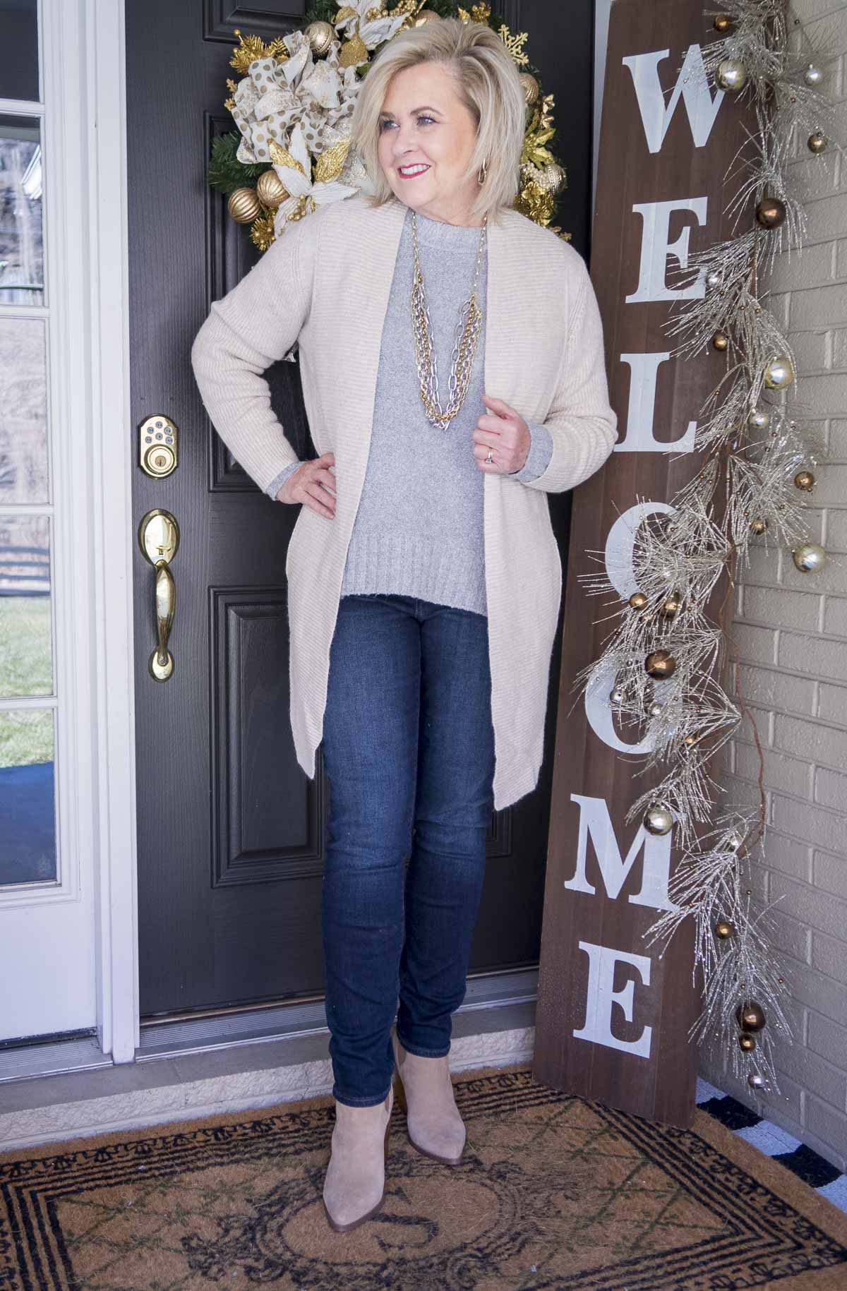 Fashion Blogger 50 Is Not Old is wearing a gray crewneck sweater, a long beige cashmere blend cardigan, a statement necklace by Kendra Scott, skinny jeggings, and pointy toe ankle boots