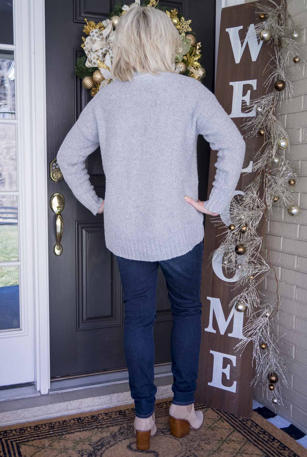 Fashion Blogger 50 Is Not Old is showing the back of a gray crewneck sweater and jeggings