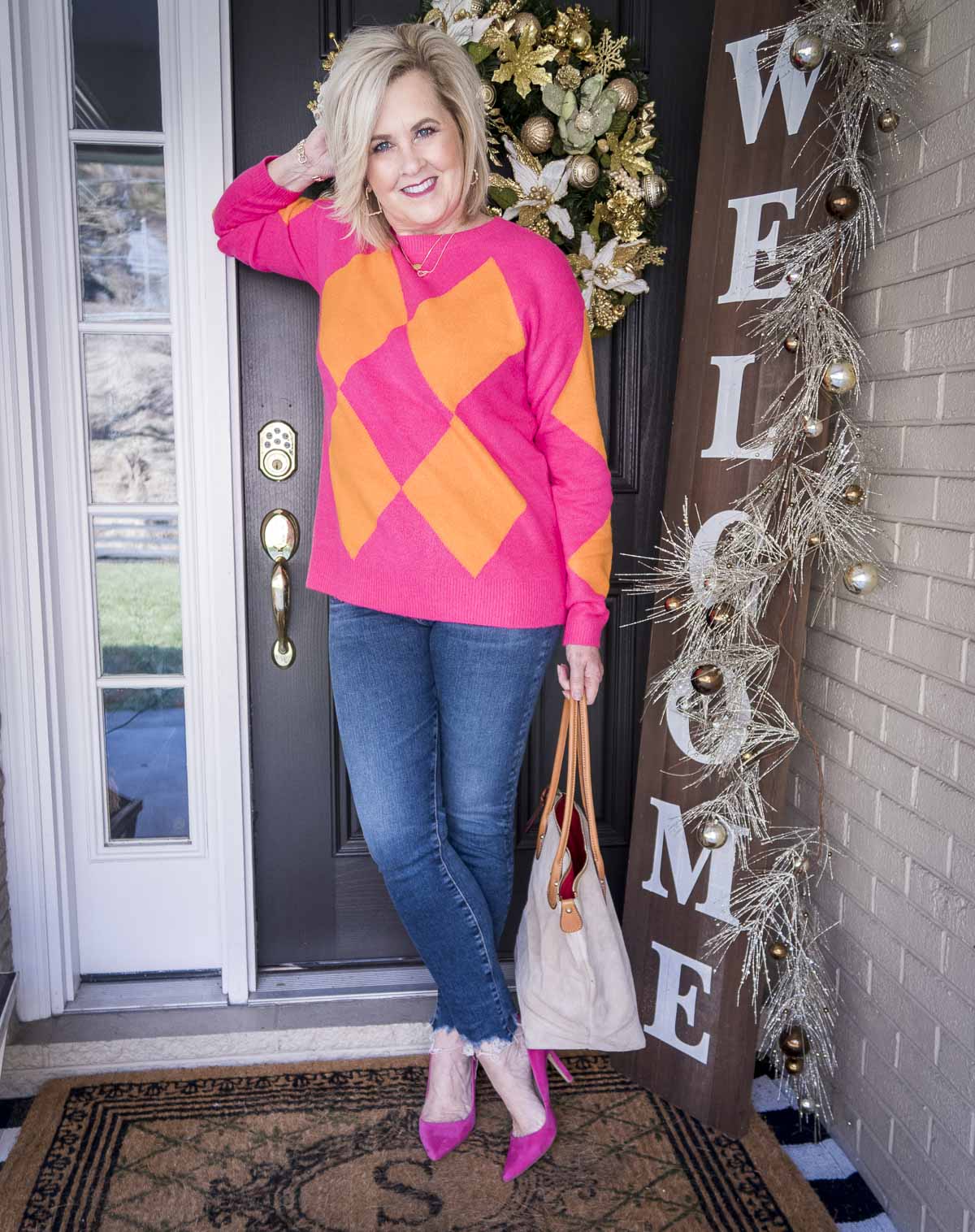 Over 40 Fashion Blogger, 50 Is Not Old is styling a bright pink and orange sweater, chewed hem skinny jeans, and pink heels