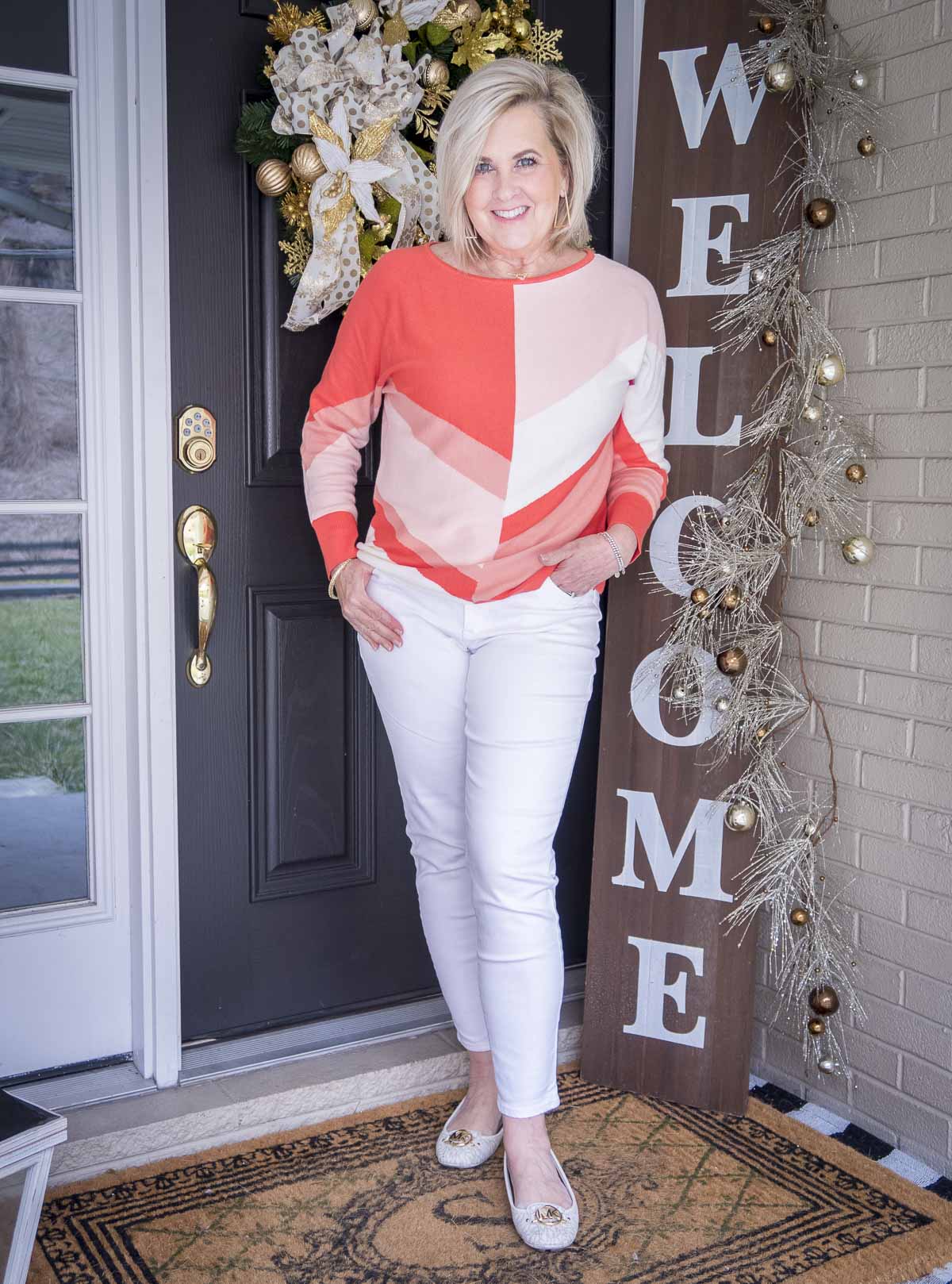Fashion Blogger 50 Is Not Old is wearing a coral colorblock sweater, white ankle jeans, and white ballet flats