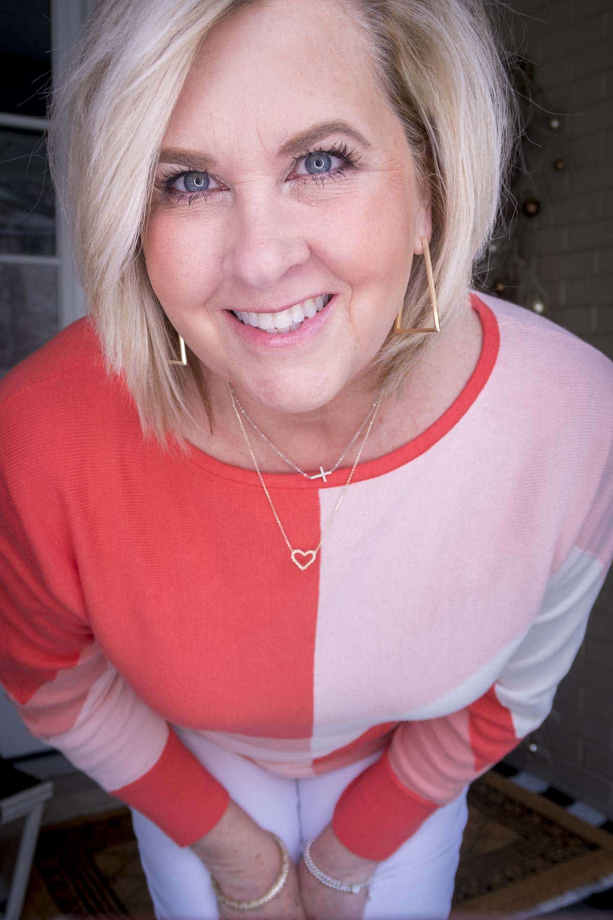 Fashion Blogger 50 Is Not Old is wearing a coral colorblock sweater with gold jewelry from Kendra Scott