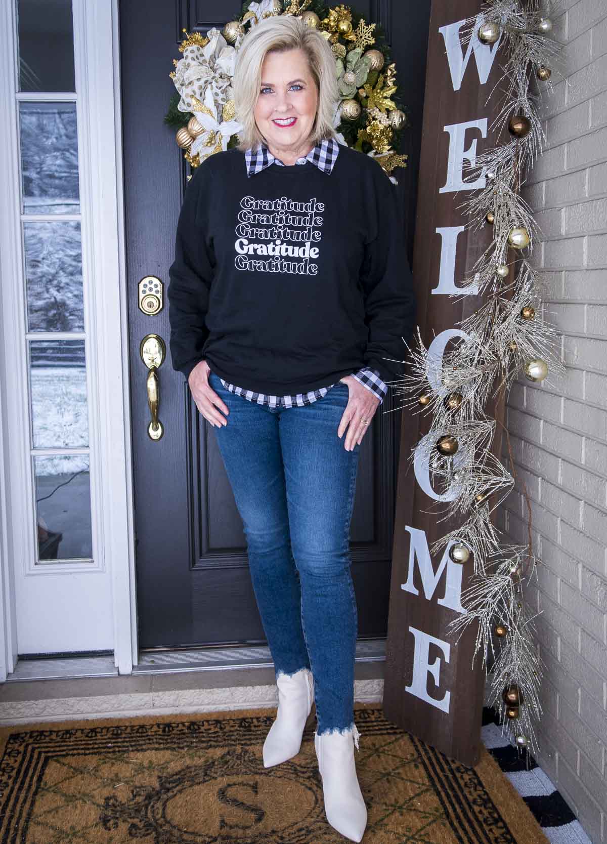 Fashion Blogger 50 Is Not Old is wearing a sweatshirt with the word gratitude, chewed hem jeans, and white ankle boots