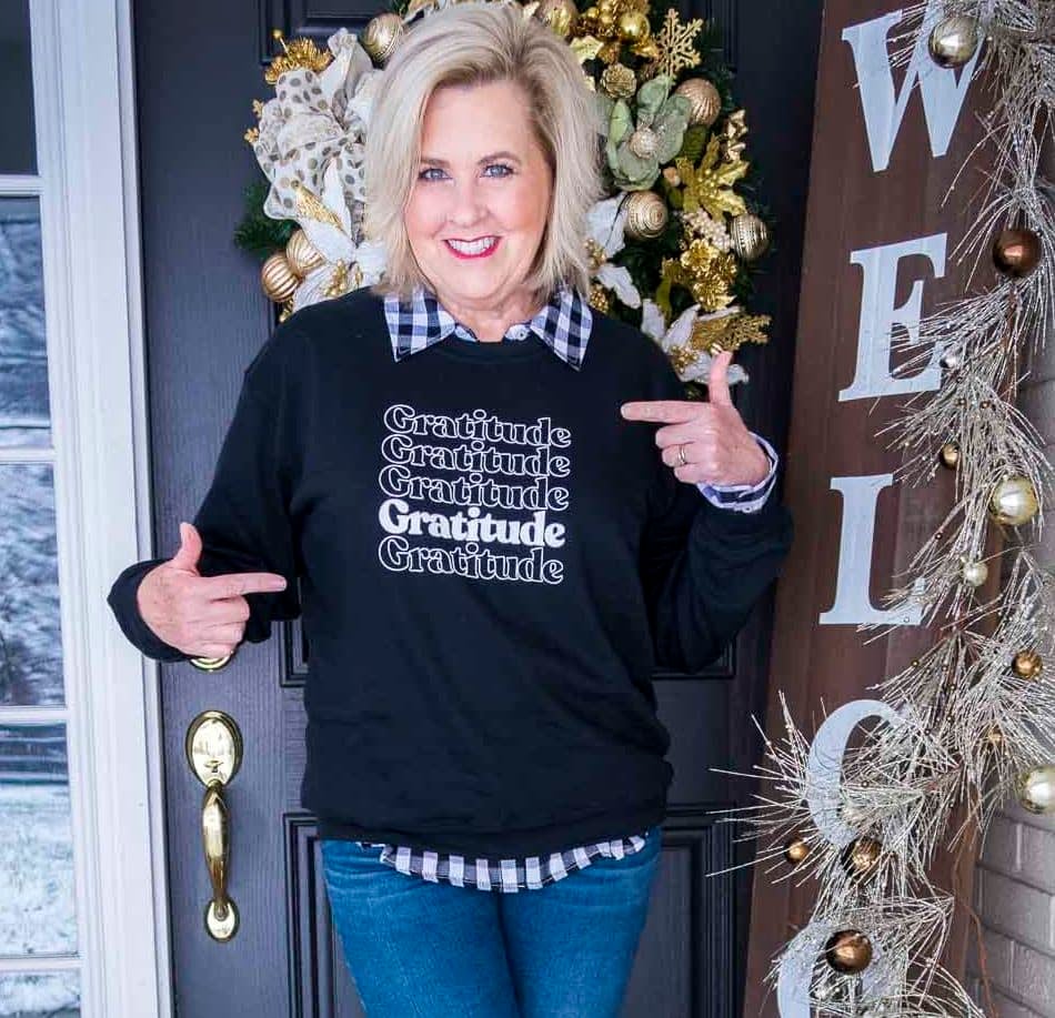 Fashion Blogger 50 Is Not Old is wearing a gratitude sweatshirt with a black and white check shirt