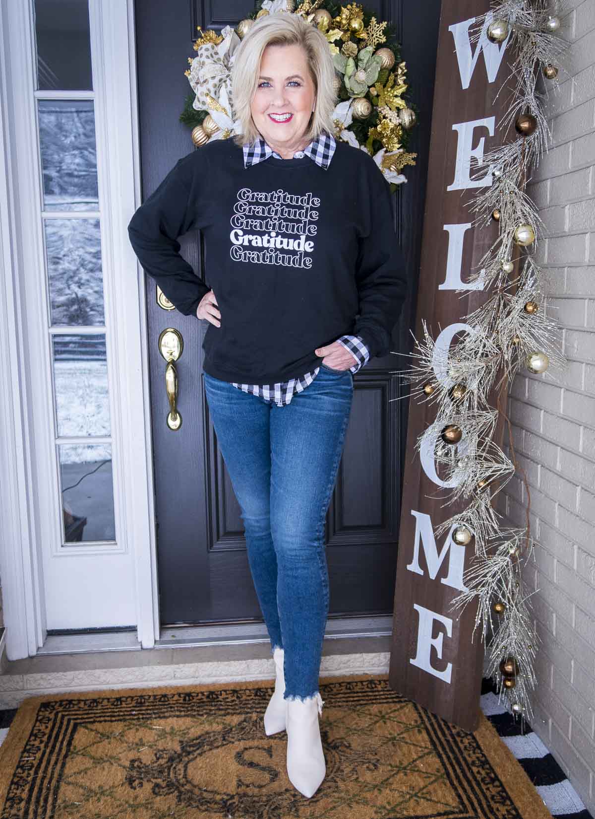 Fashion Blogger 50 Is Not Old is wearing a sweatshirt that has gratitude written on it, chewed hem jeans, and white ankle boots