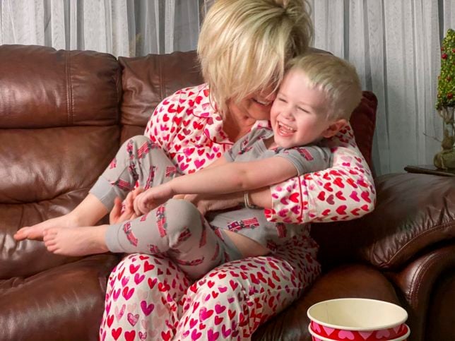 Fashion Blogger 50 Is Not Old is snuggling with her grandson while in their PJs and eating popcorn