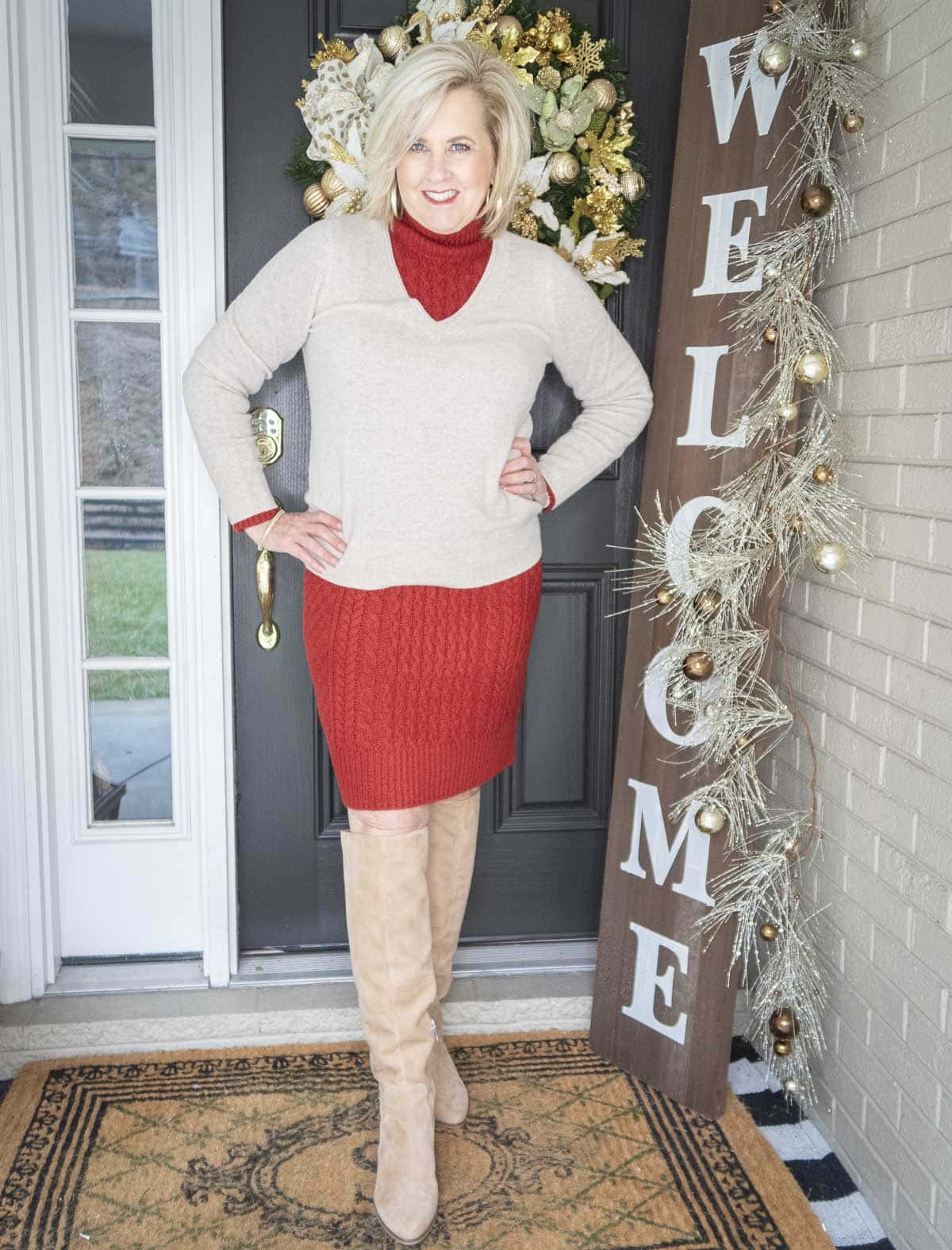 Fashion Blogger 50 Is Not Old is wearing a red sweater dress with a v-neck sweater, and tall knee boots