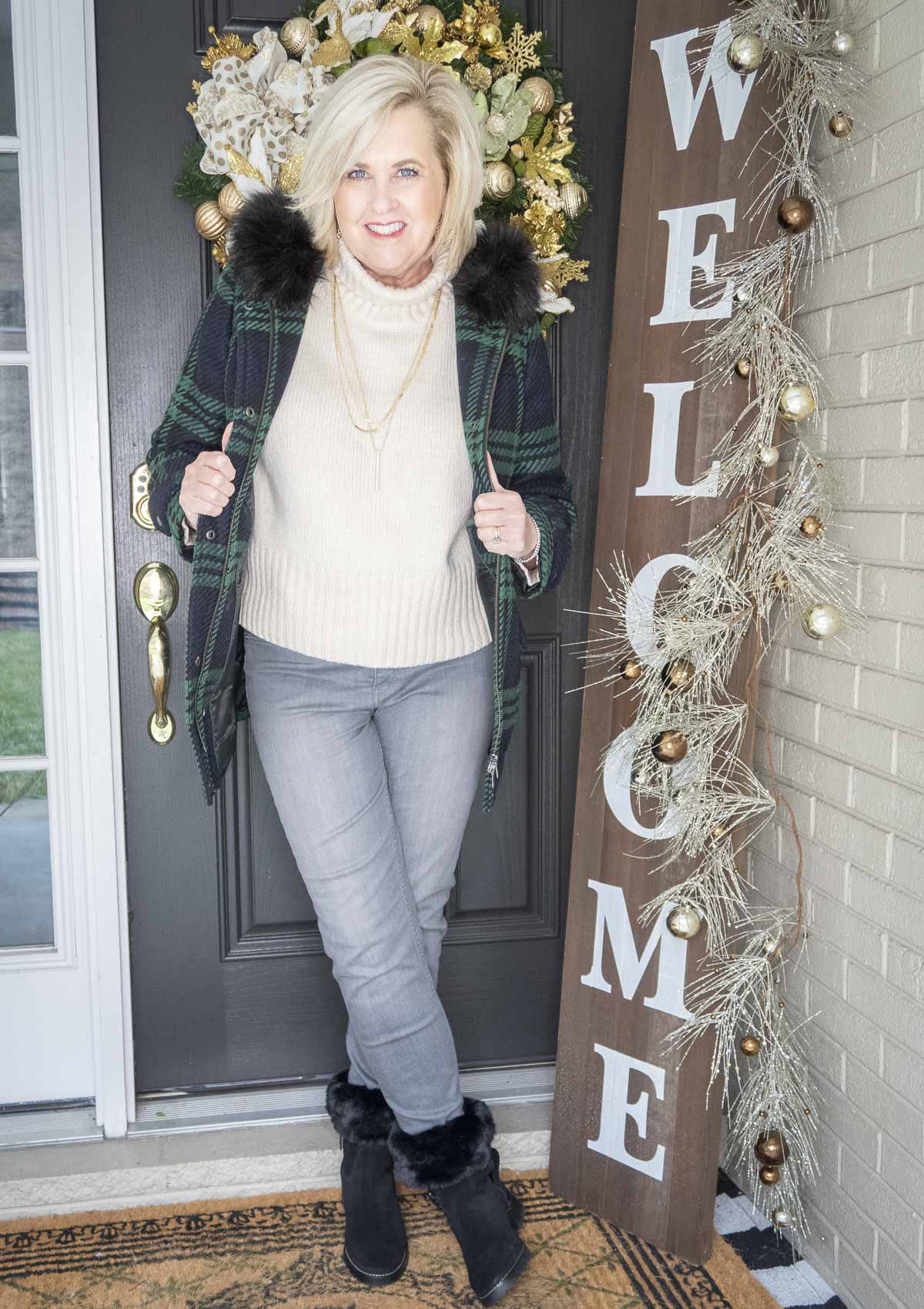 Fashion Blogger 50 Is Not Old is wearing a ivory turtleneck sweater with a navy plaid coat with a fur collar, washed gray jeans, and black fur booties