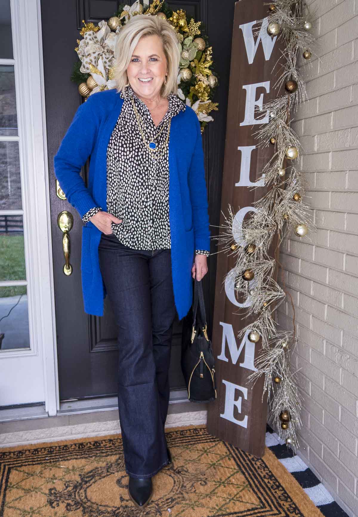 Over 40 Fashion Blogger 50 Is Not Old is wearing a bright colored cardigan over a black and white button up shirt and dark rinse jeans