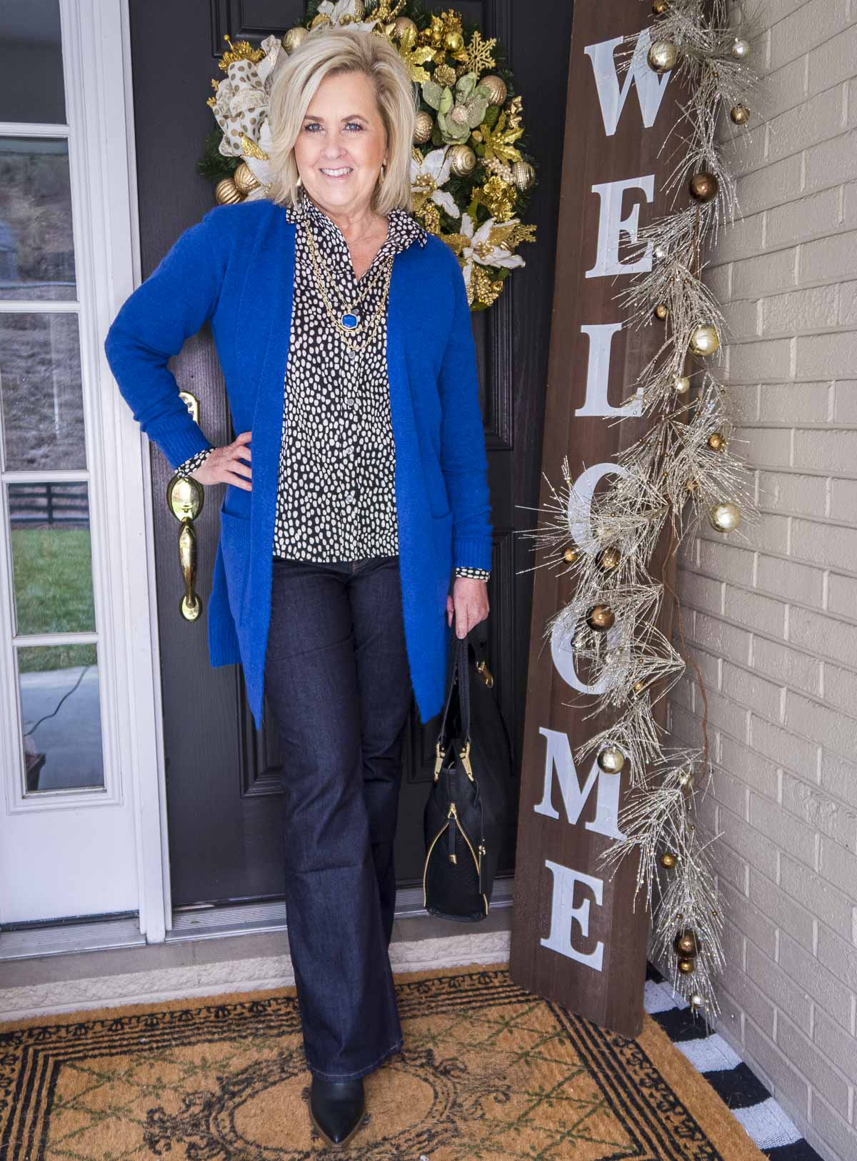 Over 40 Fashion Blogger 50 Is Not Old is wearing a bright blue colored cardigan over a button up shirt and dark rinse jeans