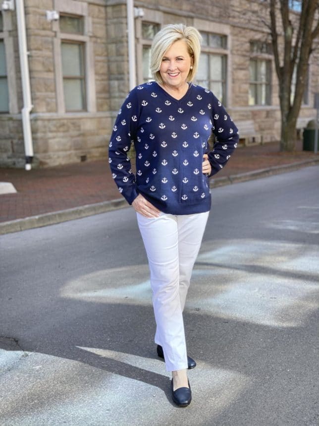 Fashion Blogger 50 Is Not Old is looking modern and stylish in this navy sweaters with white anchors, white ankle pants, and navy flats