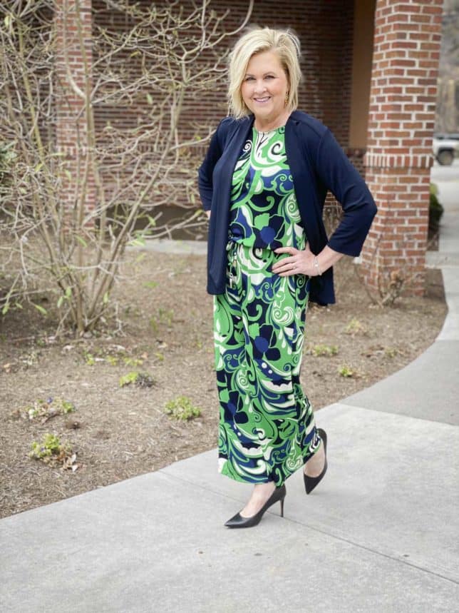 Fashion Blogger 50 Is Not Old is wearing a printed jumpsuit with a navy jacket that would be perfect for on the go