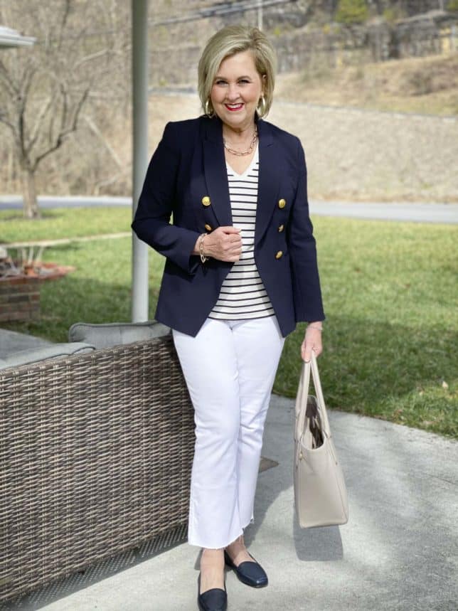Fashion Blogger 50 Is Not Old dressed like a french woman for International Women's Day in stripes, a navy blazer, white jeans, and navy flats