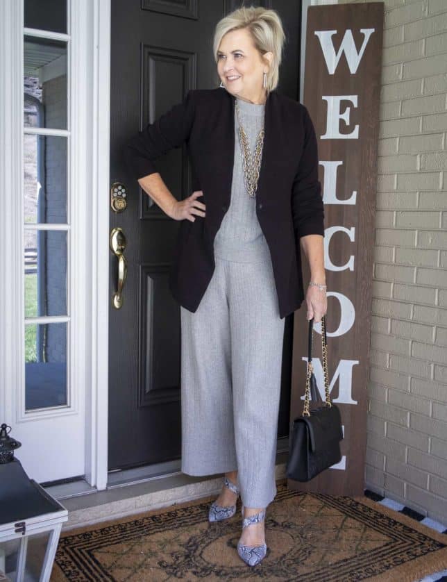 Fashion Blogger 50 Is Not Old is wearing a black blazer, a gray cropped loungewear set from Target, gold jewelry from Kendra Scott, a Tory Burch handbag, and snakeskin heels