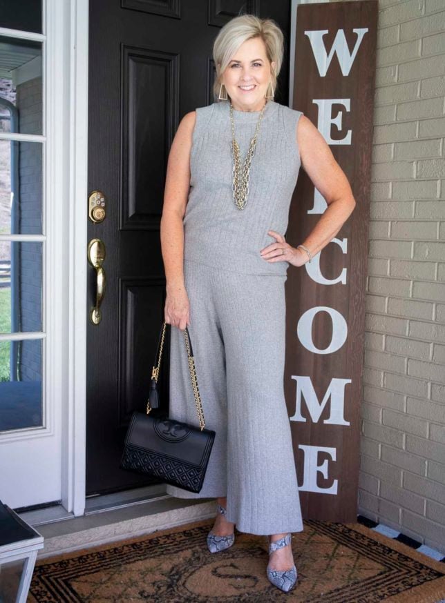 Fashion Blogger 50 Is Not Old is wearing a gray cropped loungewear set from Target with gold jewelry, a Tory Burch handbag, and snakeskin heels