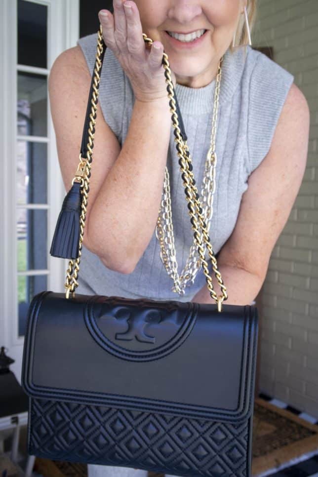 Fashion Blogger 50 Is Not Old is showing a Tory Burch handbag with a convertible chain