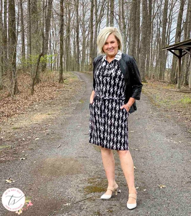 Fashion Blogger 50 Is Not Old is wearing a black and white bit and bridle dress with a black front zip jacket by Chicos