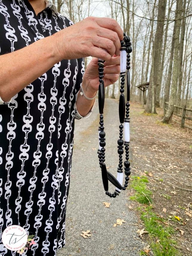 Fashion Blogger 50 Is Not Old is showing a black and white necklace that she has doubled