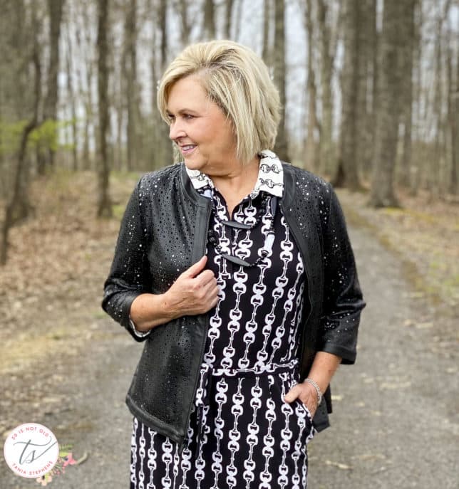 Fashion Blogger 50 Is Not Old is wearing a black and white bit and bridle dress with a black front zip jacket and a black and white necklace